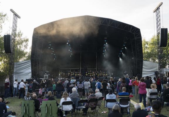 A stage with lights and speakers, and an audience sitting in front of it