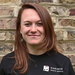 Woman standing in front of brick wall wearing Haringey Music Service t-shirt.