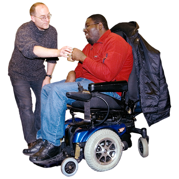 A man helping another man in a wheelchair with a drink