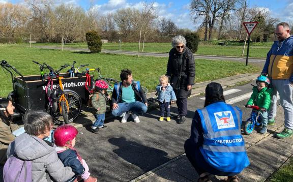 Group of parents, toddlers and instructors at the park with little bikes