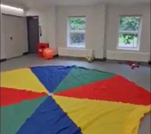 A large room with a colourful circular mat on the floor