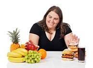 A woman at a table with healthy and unhealthy foods