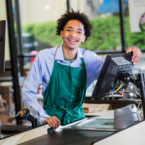 young person smiling working at a register 