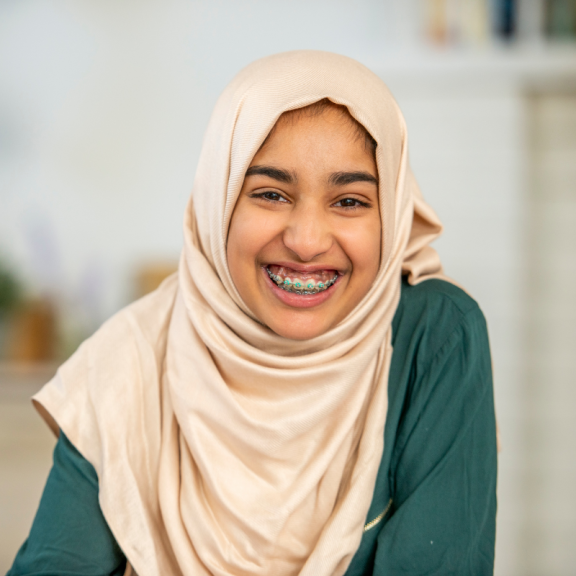 young person smiling with braces wearing a Hijab