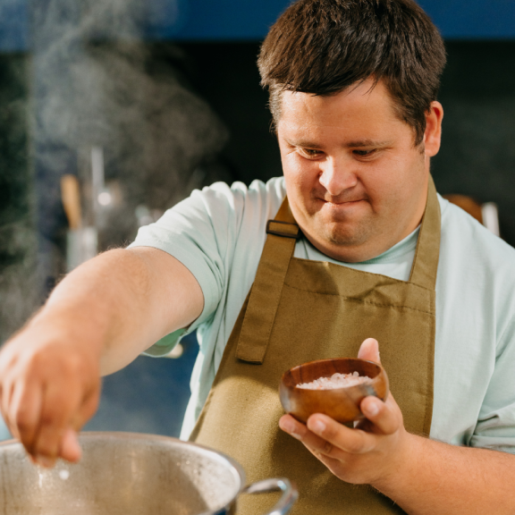 young person cooking in a kitchen wearing an apron