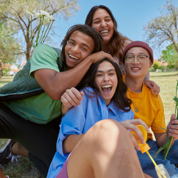 four young people smiling in a park setting