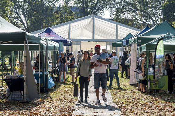 A couple with a baby, walking among stalls in a park
