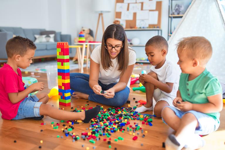 Three children and an adult playing with blocks.