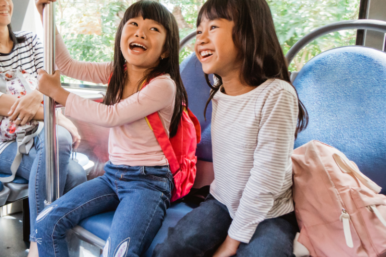 two children on public transportation smiling 