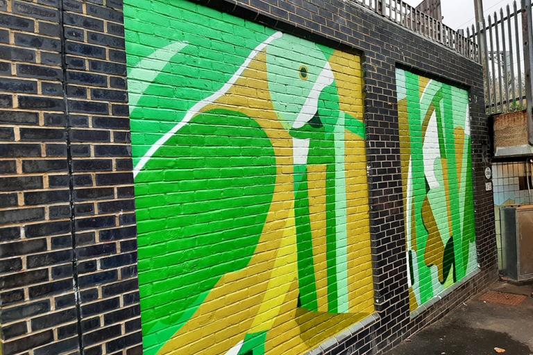 Murals depicting a tropical bird and plant life in abstract blocks of green, yellow and brown 