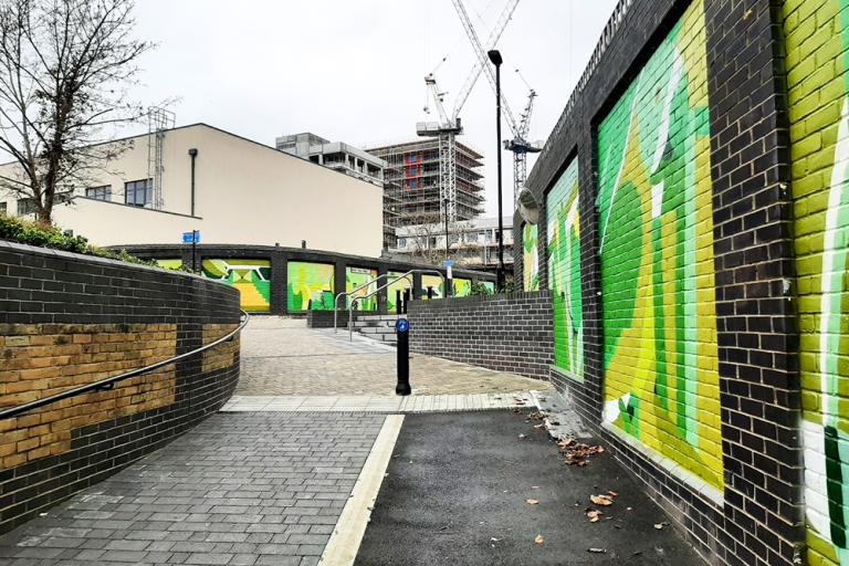 An urban pedestrian alleyway with murals to one side