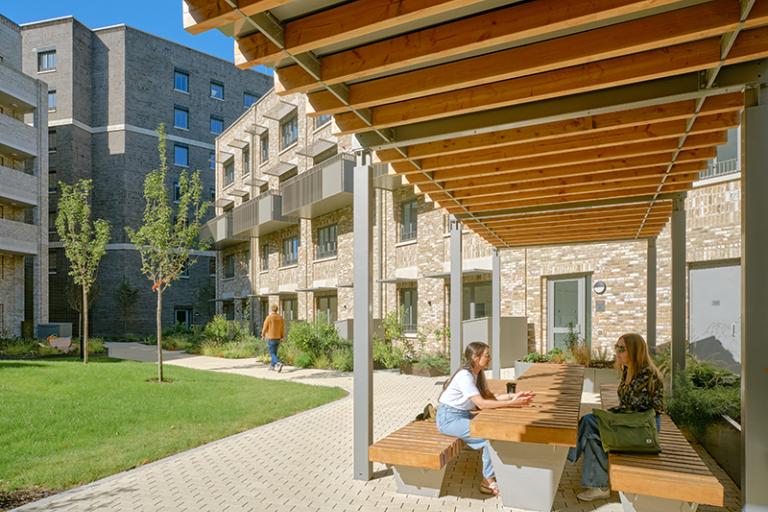 People sitting on outdoor benches in a modern apartment development
