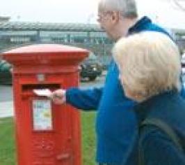 A man and woman posting a letter