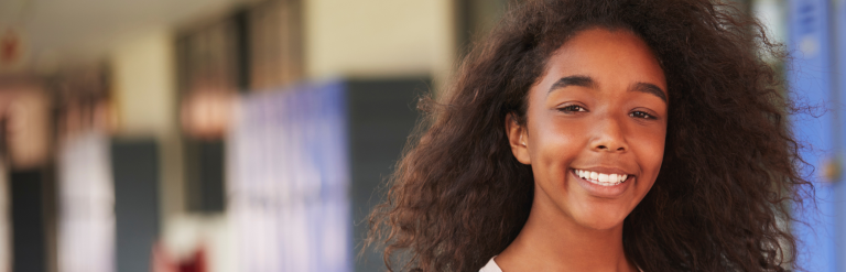 Young person in a school hallway smiling