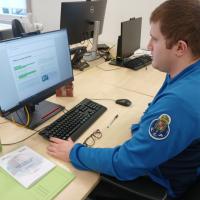 young adult sitting at a desk in front of a computer in an office setting