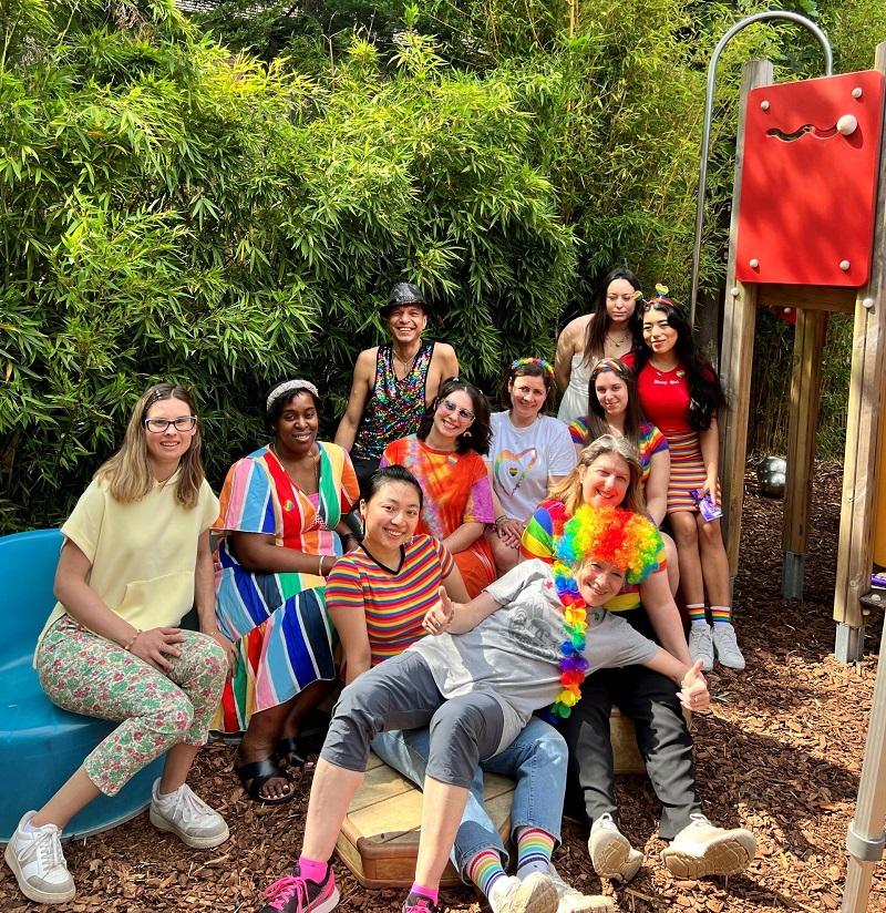 Nursery staff in a group photo smiling in celebratory rainbow pride-coloured clothing