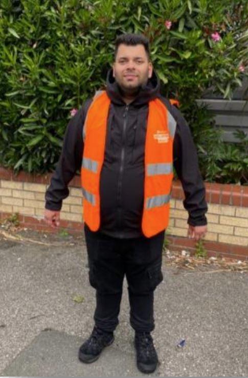 image of a person smiling at the camera with a bright orange vest on